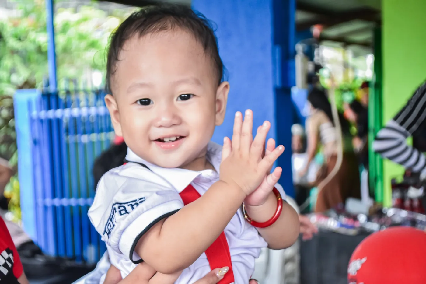 Baby smiling and clapping at a baptism celebration
