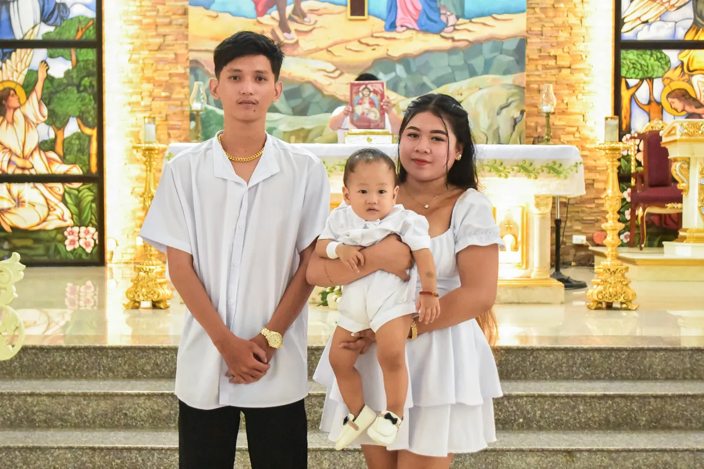 Family of three standing at the church altar after a baptism ceremony