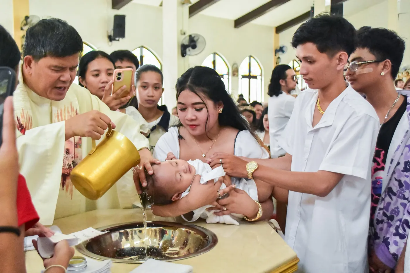 Priest pouring water over a baby during a baptism ceremony at a church, photographed by Dana Shotz